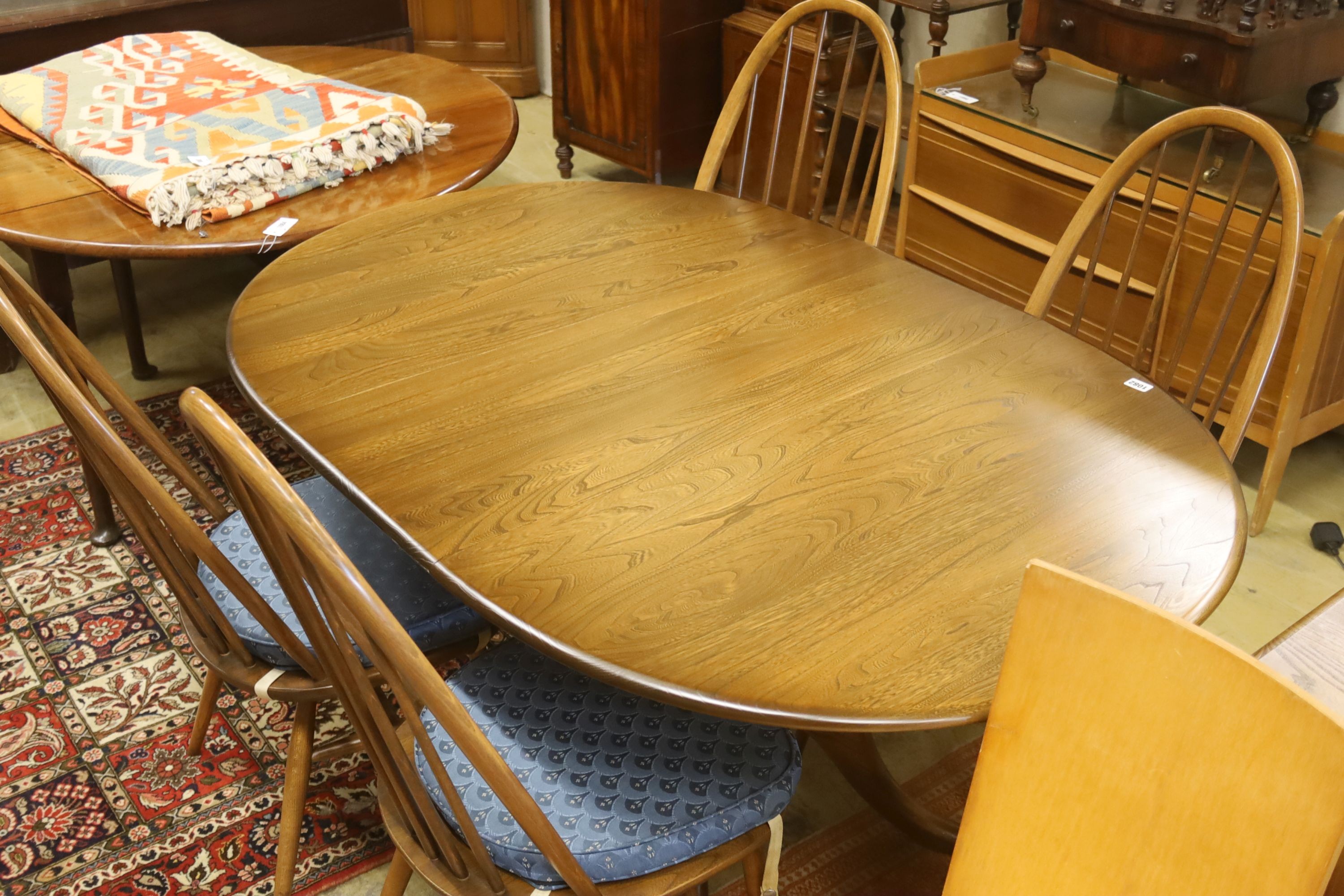 An Ercol elm oval extending dining table, 148cm extended, width 97cm, height 74cm, together with a pair of Ercol elm and beech comb back dining chairs